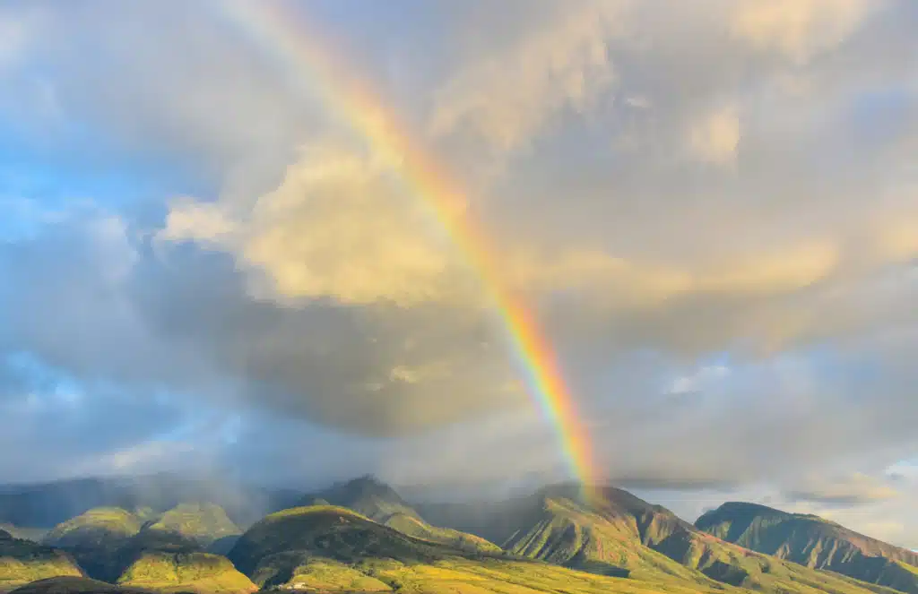 A rainbow over the mountains in Hawaii shows how remote the small island can be. This is why shipping companies to Hawaii are so sought after.