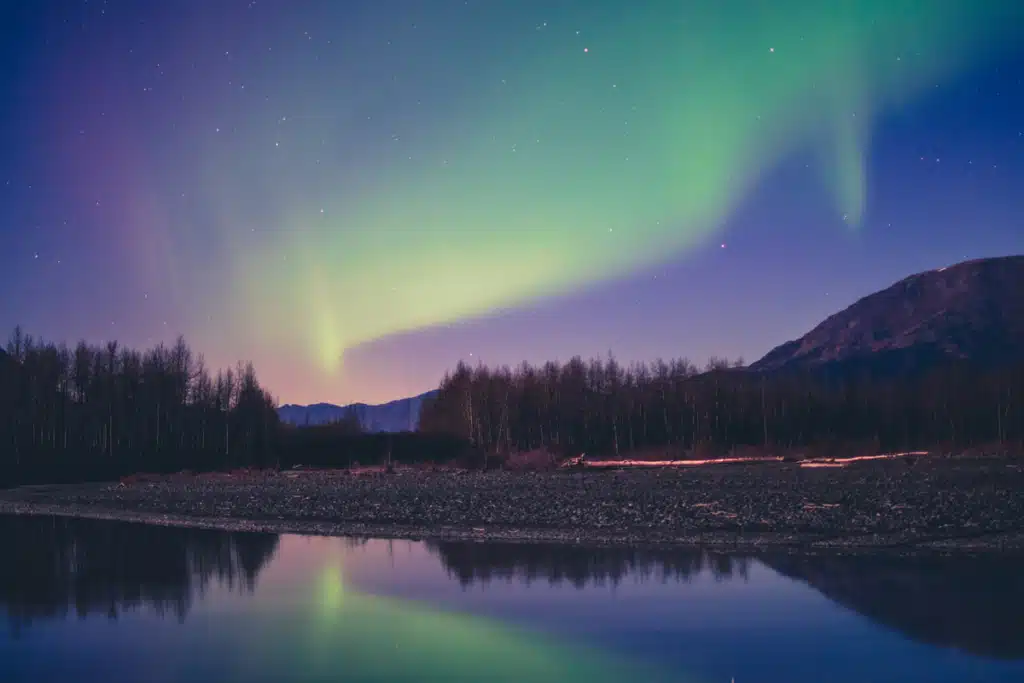The northern lights shine over a lake in Alaska.