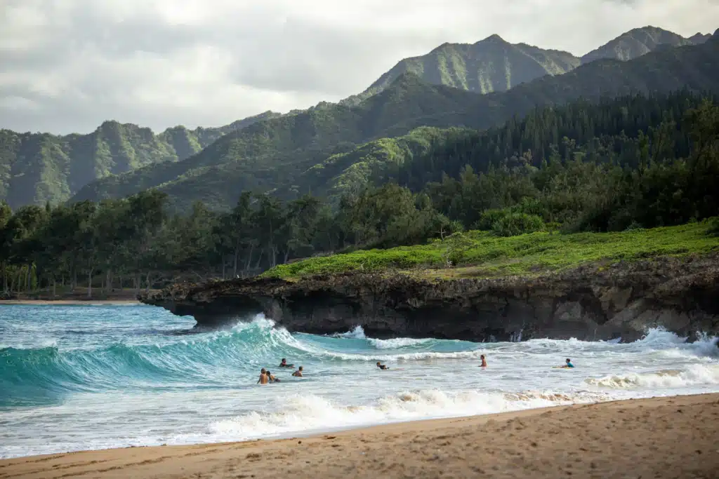 A busy beach on Hawaii with surfers on large waves. Shipping to Hawaii can be as smooth as this!