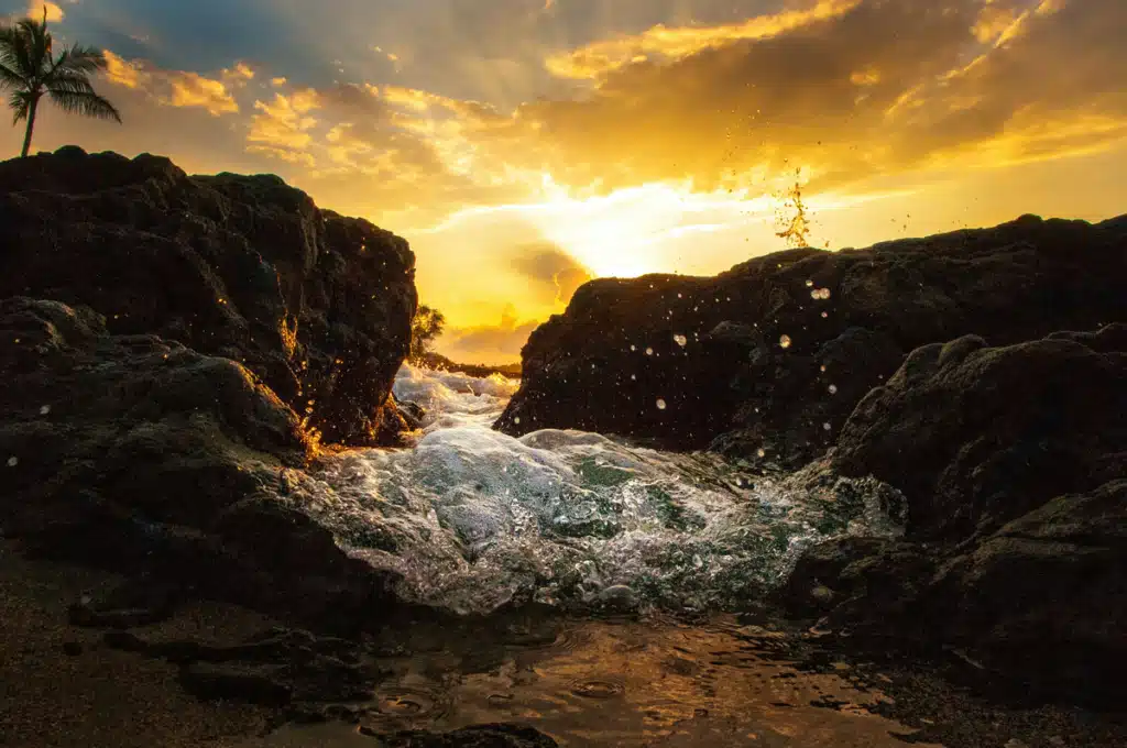 A tide coming in during sunset in Hawaii on a beach.