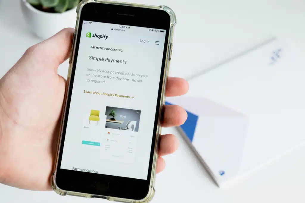 Someone is using the Shopify app from their smartphone, setting up their ecommerce business before signing up for our mail consolidation services.