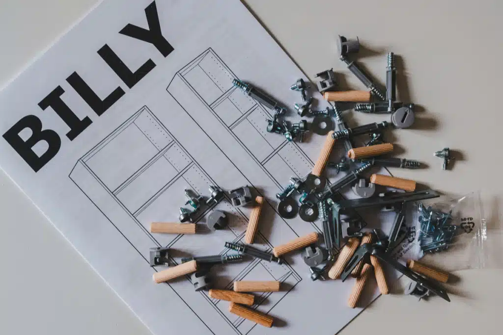 An Ikea Billy bookcase manual, laying underneath an array of nails and pegs.