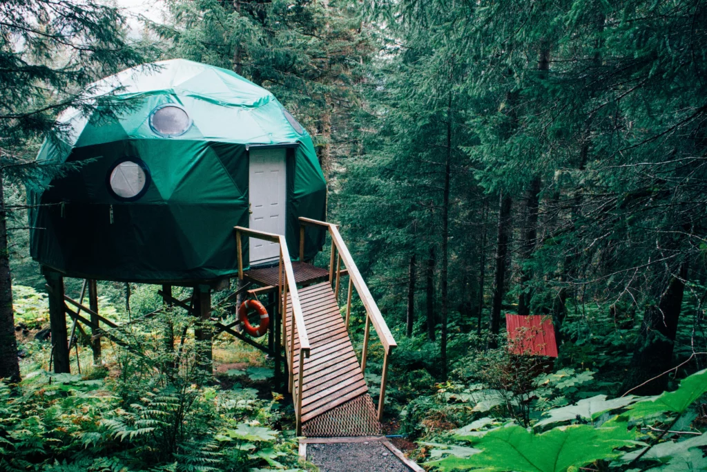 A raised dome cabin in the remote woods in Alaska. Someone staying in a place like this with limited access should look into the cheapest way to ship household goods to Alaska.