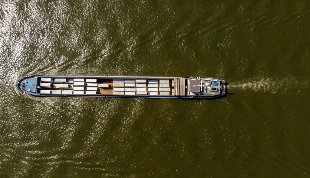 A top-down view of a small cargo vessel in the sea transporting ecommerce international shipping.