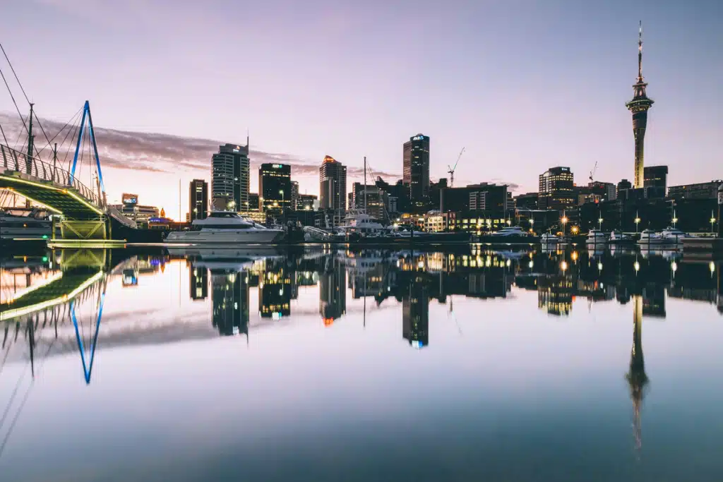 A city skyline reflects on the water as the sky dims in New Zealand.