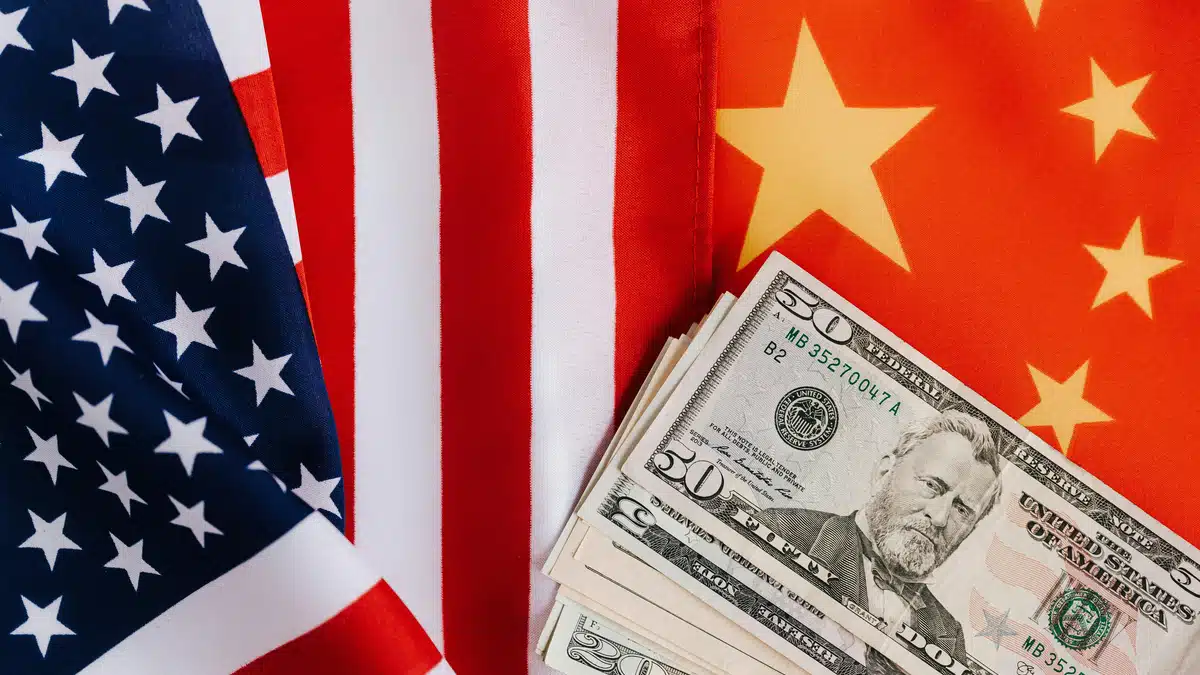 Le spedizioni dagli Stati Uniti alla Cina sono rappresentate da una bandiera statunitense a sinistra, da una cinese a destra e da un po' di contanti in dollari USA disposti al centro, come un ventaglio.