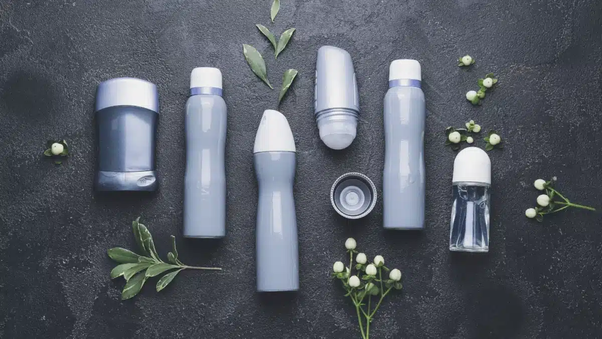 A selection of various sizes of aerosol cans against a dark grey background with leaves and flowers about. Can you ship aerosol cans like this? Find out here.