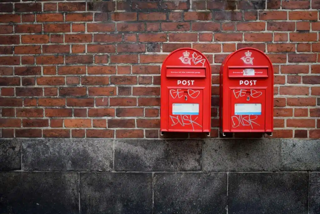 Two red post boxes against a brick wall, likely full of compostable mailers!