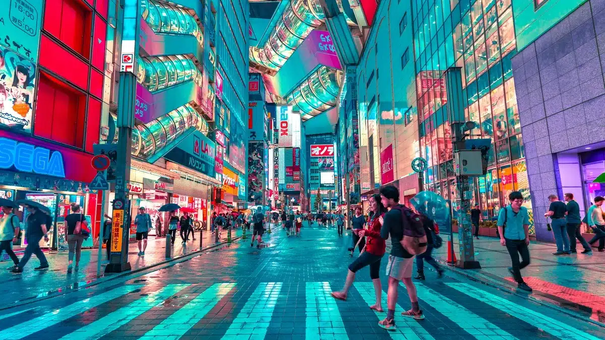 A busy city street is lit up during night time in Japan. Many people in these cities have access to American goods by shipping to Japan from US.