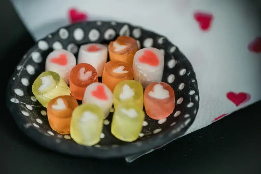 A black ceramic candy dish with small white polka dotsis full of round, heart-shaped candy.