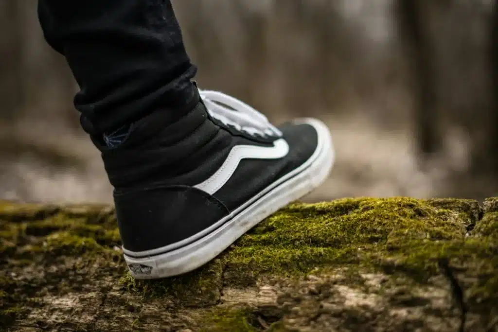 Someone is stepping over a mossy log with slip-resistant shoes from Vans so they don't slip. Find a cheaper dupe from Walmart and ship it anywhere with PostFromUS.