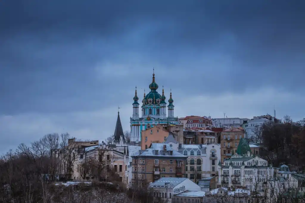 A city in Ukraine, with the sun setting and a cloudy sky. There is a tall building in the middle, likely historical. Shipping to Ukraine from US is easy with PostFromUS.