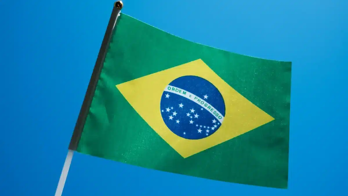 The Brazilian flag is flown, a blue sky behind it.