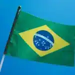 The Brazilian flag is flown, a blue sky behind it.