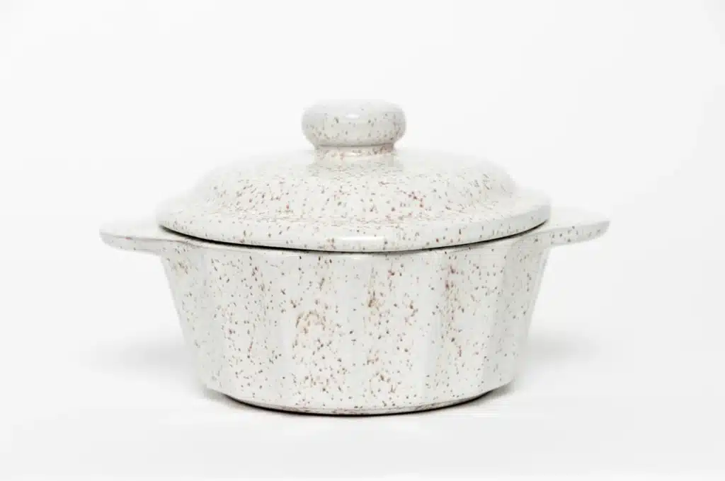 A light speckled ceramic unique candy dish with lid. White background.